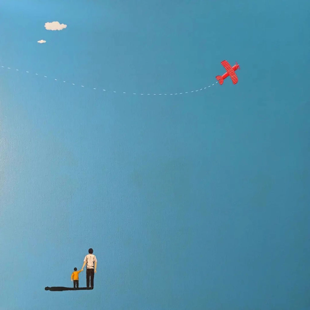 A man and child watching a small red plane in a blue sky