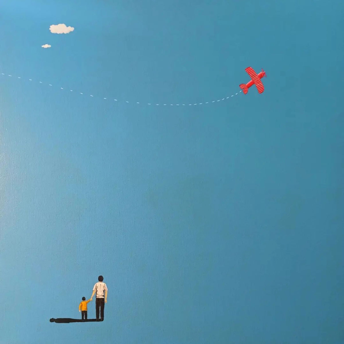 A man and child watching a small red plane in a blue sky