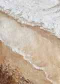 White surf washing over beige sand seen from above