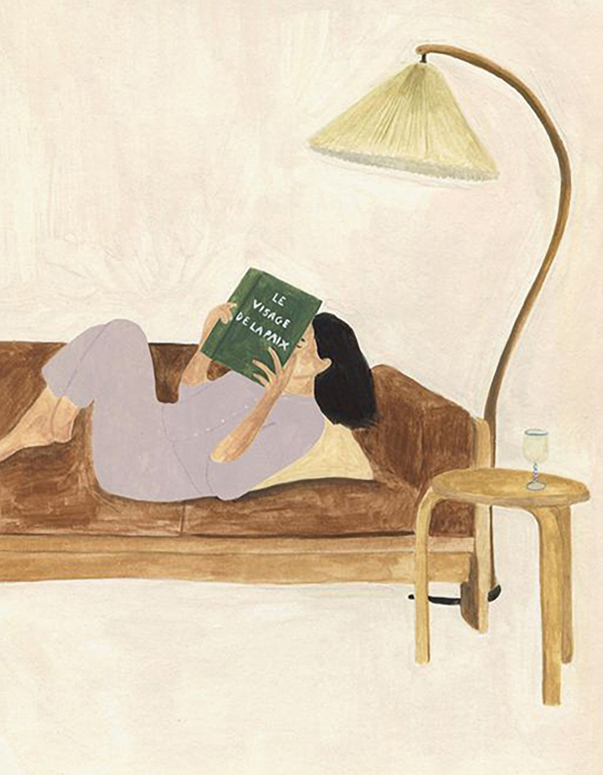 A woman stretched on a sofa reading beneath a tall floor lamp