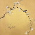 A bird on an arching blossom branch over gold, with tiny fish below