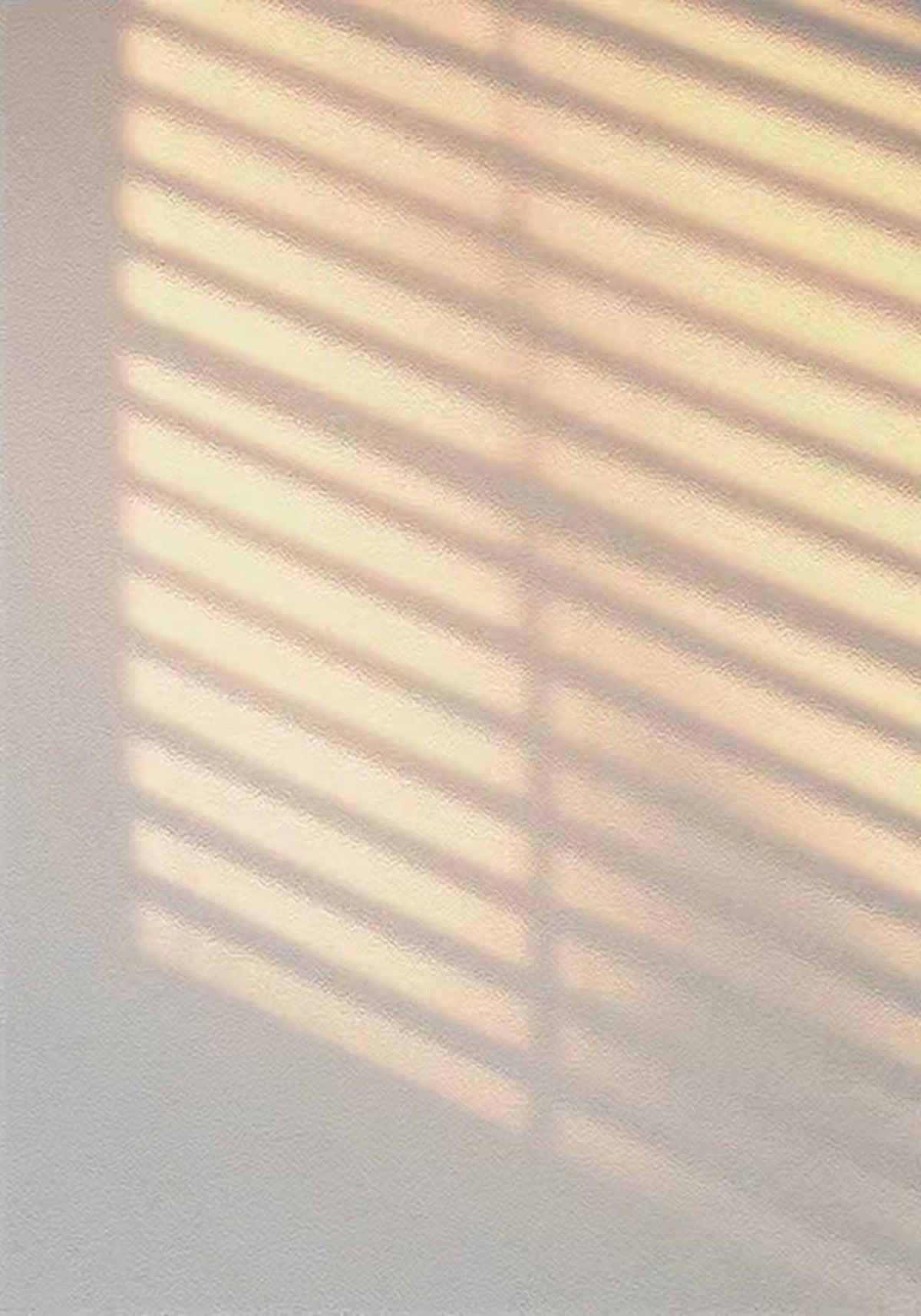 Striped light from a window blind on a pale wall