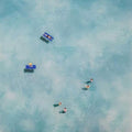 Tiny swimmers and floats drifting in a hazy blue sea from above