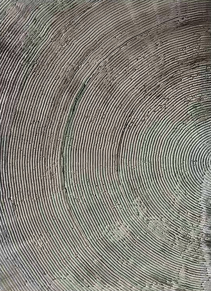 Fine concentric grooves carved in grey textured paint