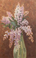 A spray of lilac in a slim glass vase against warm brown
