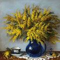 A yellow mimosa bouquet in a cobalt vase beside a teacup