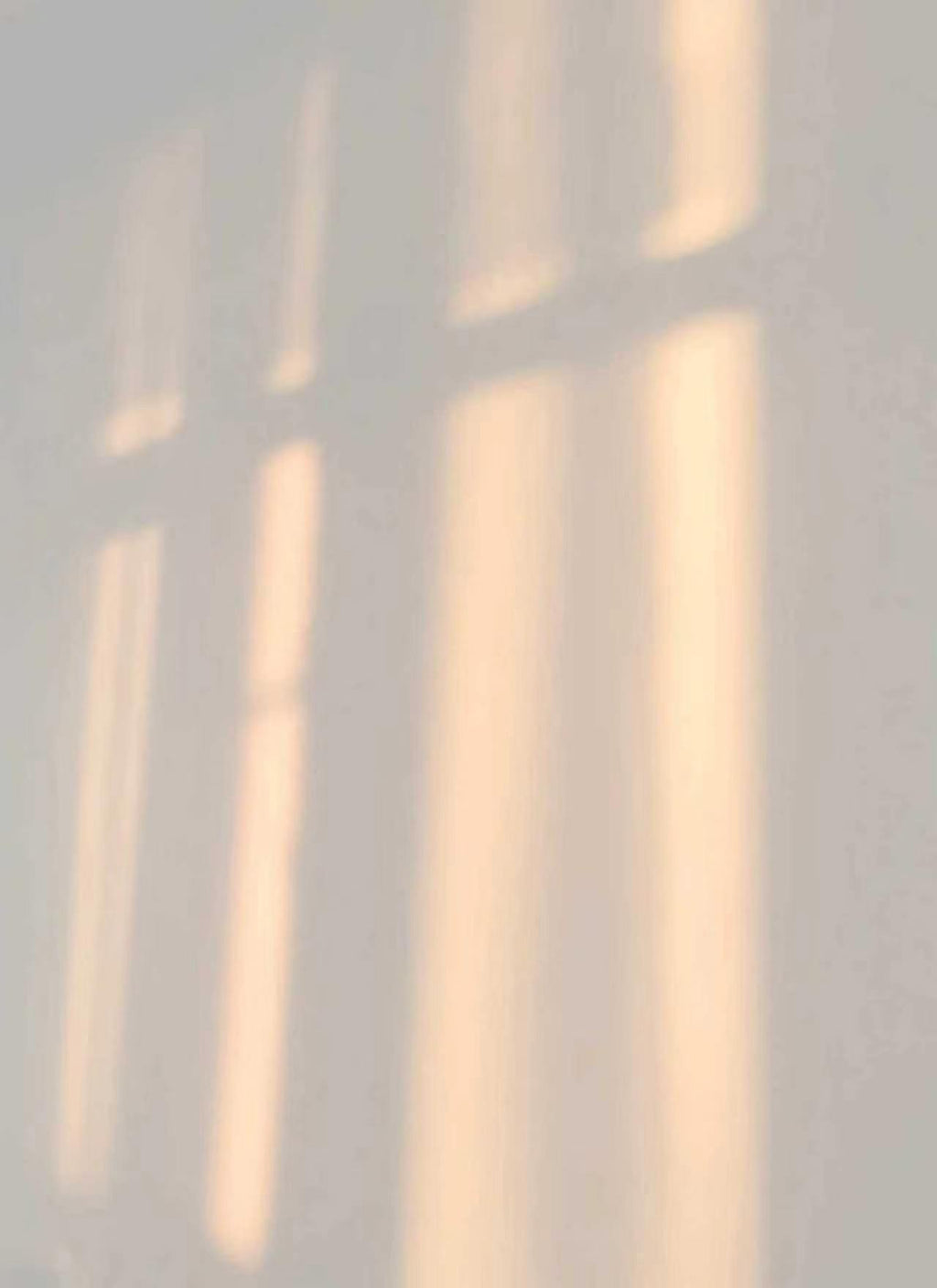 Soft beams of window light on a pale grey wall