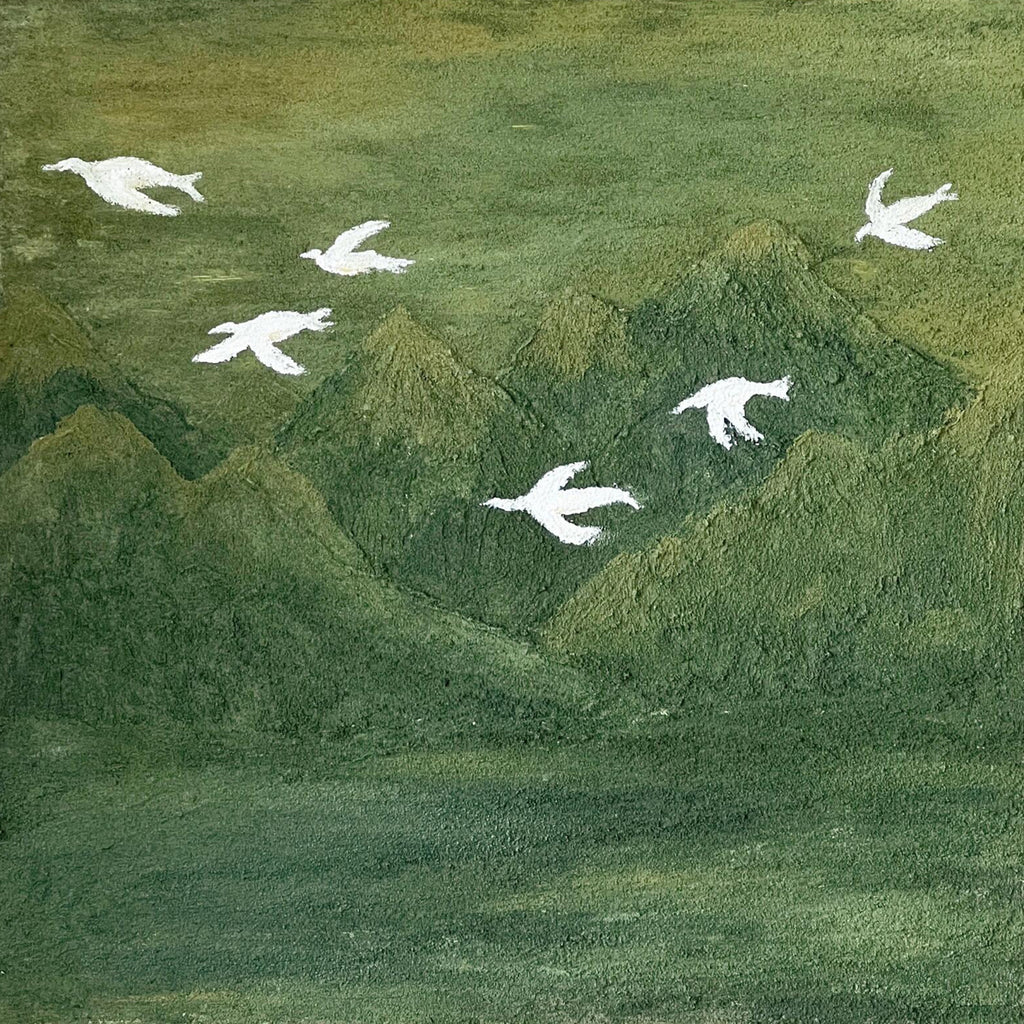 White doves flying above rolling deep-green hills