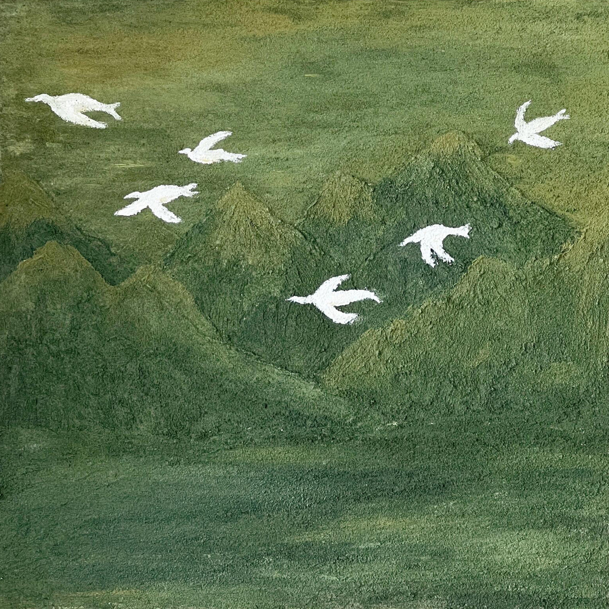 White doves flying above rolling deep-green hills