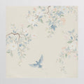 A pale blue bird flying beneath soft blossom branches on cream