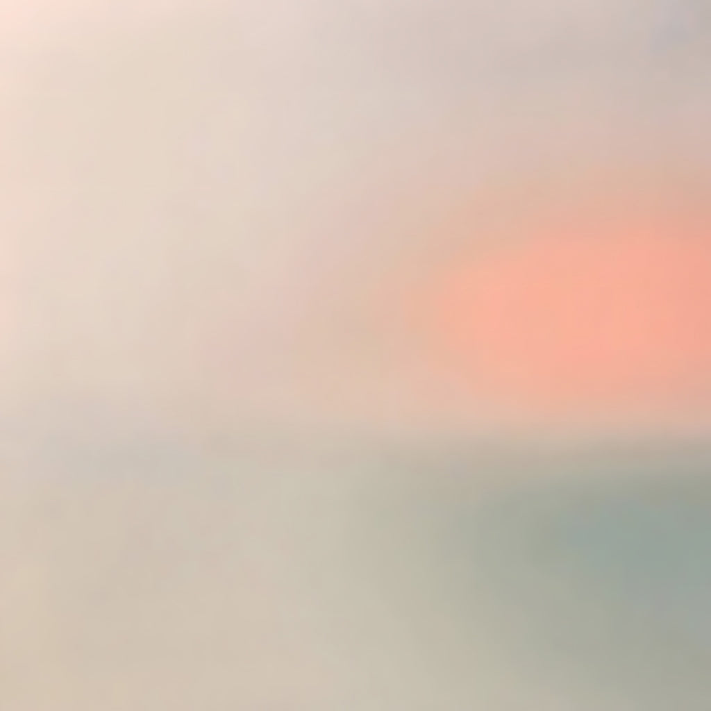 A soft coral sun glowing through a pale haze of grey and mint