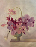 Pink, plum and mauve orchids spilling from a small green pot on a pale ledge
