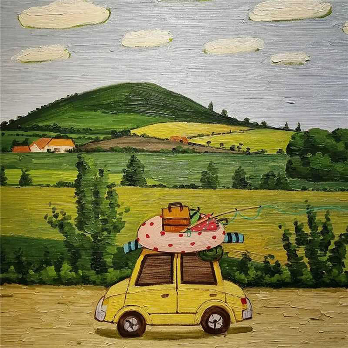 A little yellow car with luggage and a dotted float on the roof, driving past green fields and a hill