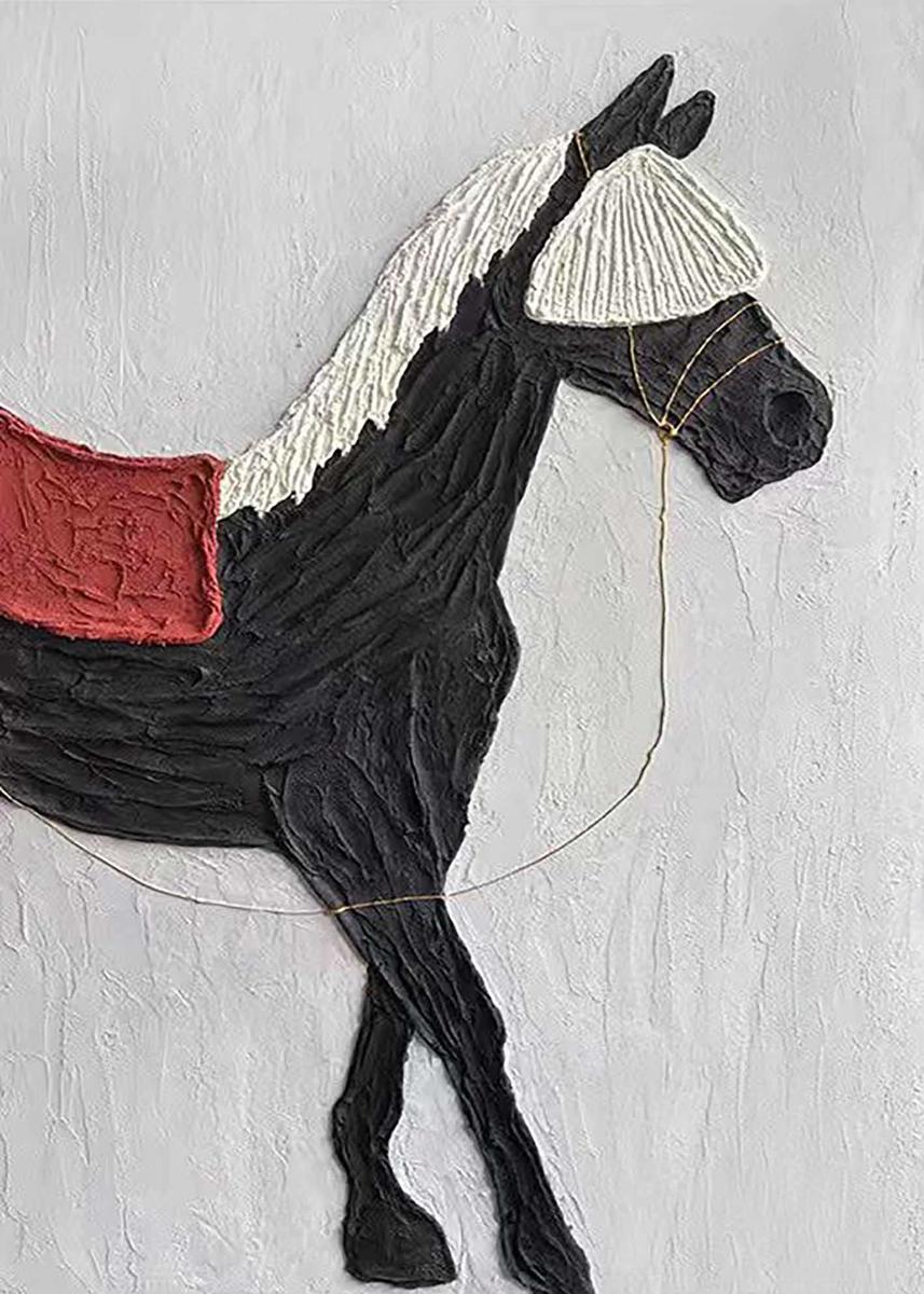 A black horse with a white mane and red saddle in sculpted relief