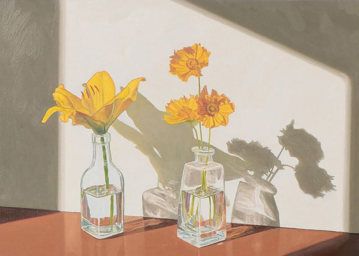 A yellow lily and orange coreopsis in two glass bottles casting soft shadows on a sunlit wall