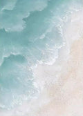 Foamy turquoise waves rolling onto pale sand, seen from above