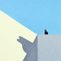 A small black cat perched on a grey wall, its long shadow on a pale yellow facade under blue sky