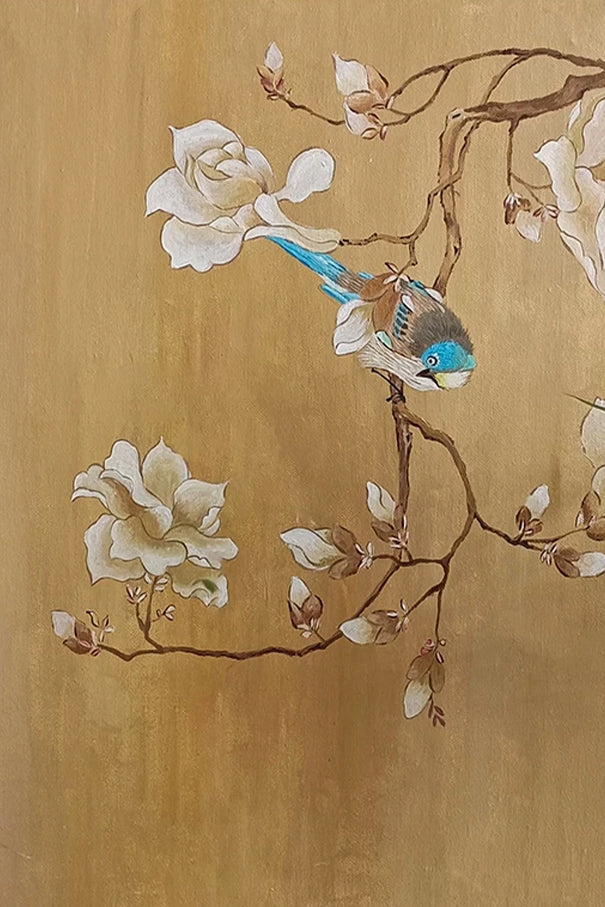 A blue wren on a magnolia branch over a warm golden ground