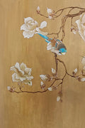 A blue wren on a magnolia branch over a warm golden ground