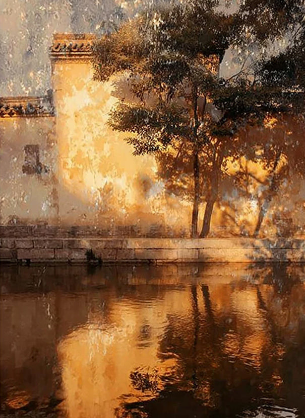 A warm-lit old wall and trees reflected in still water at golden hour