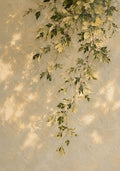A spray of green and gold leaves hanging down a sunlit textured stucco wall