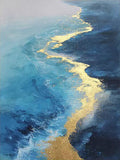 A ribbon of gold leaf tracing the line where turquoise surf meets a deep navy sea