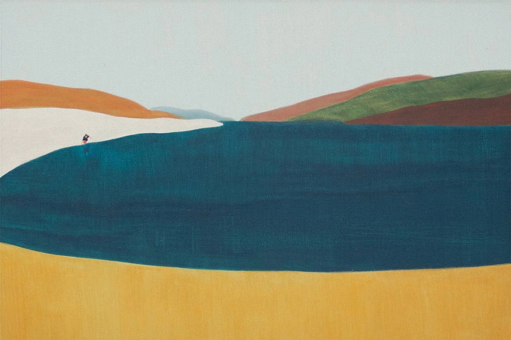 A deep teal lake among rolling hills of orange, green and mustard, one tiny figure on the shore