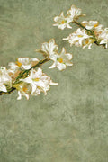 A spray of white Easter lilies reaching across a textured sage-green ground