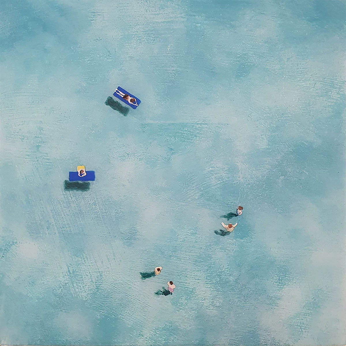Swimmers and blue floats drifting on bright turquoise water, seen from above