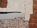 A flat abstract interior of cream walls, a black shelf, wood panels and a zebra-striped rug