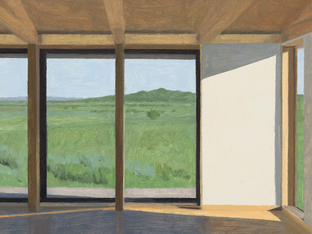 A sunlit wooden room with tall windows looking out onto green rolling grassland