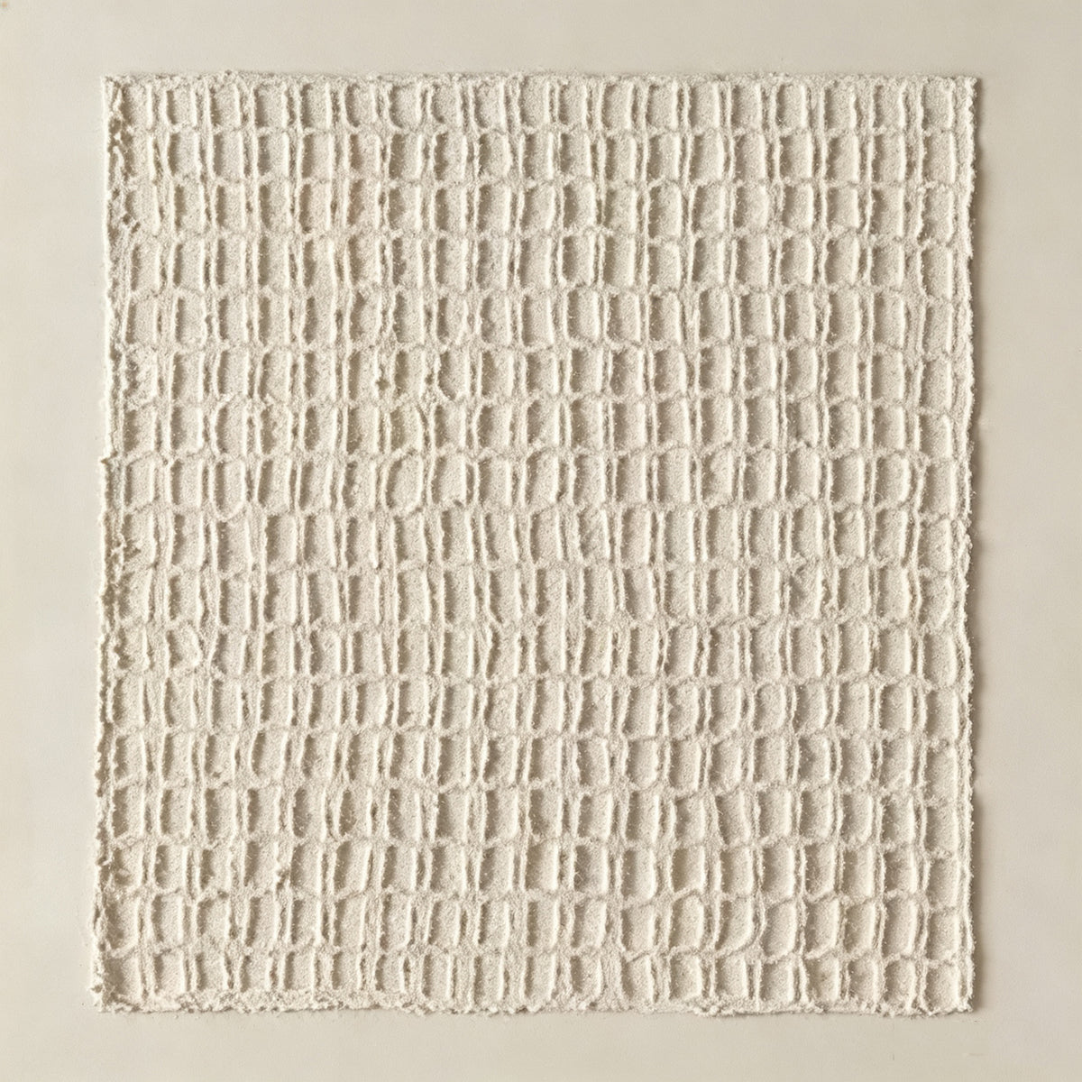 A hand-sculpted lattice of raised ivory squares on a cream ground