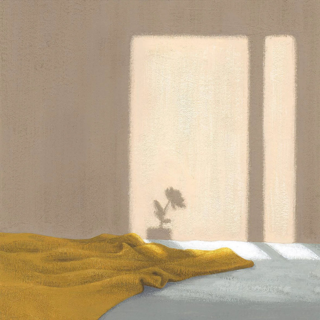Sun from a window falling on a beige wall with a flower's shadow, above a rumpled mustard blanket