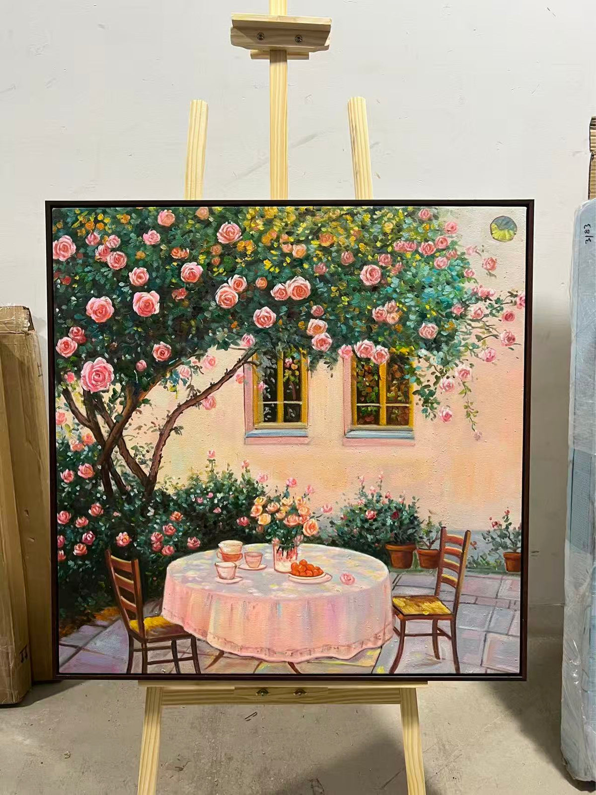 A table set for two beneath a flowering tree outside a stone house.