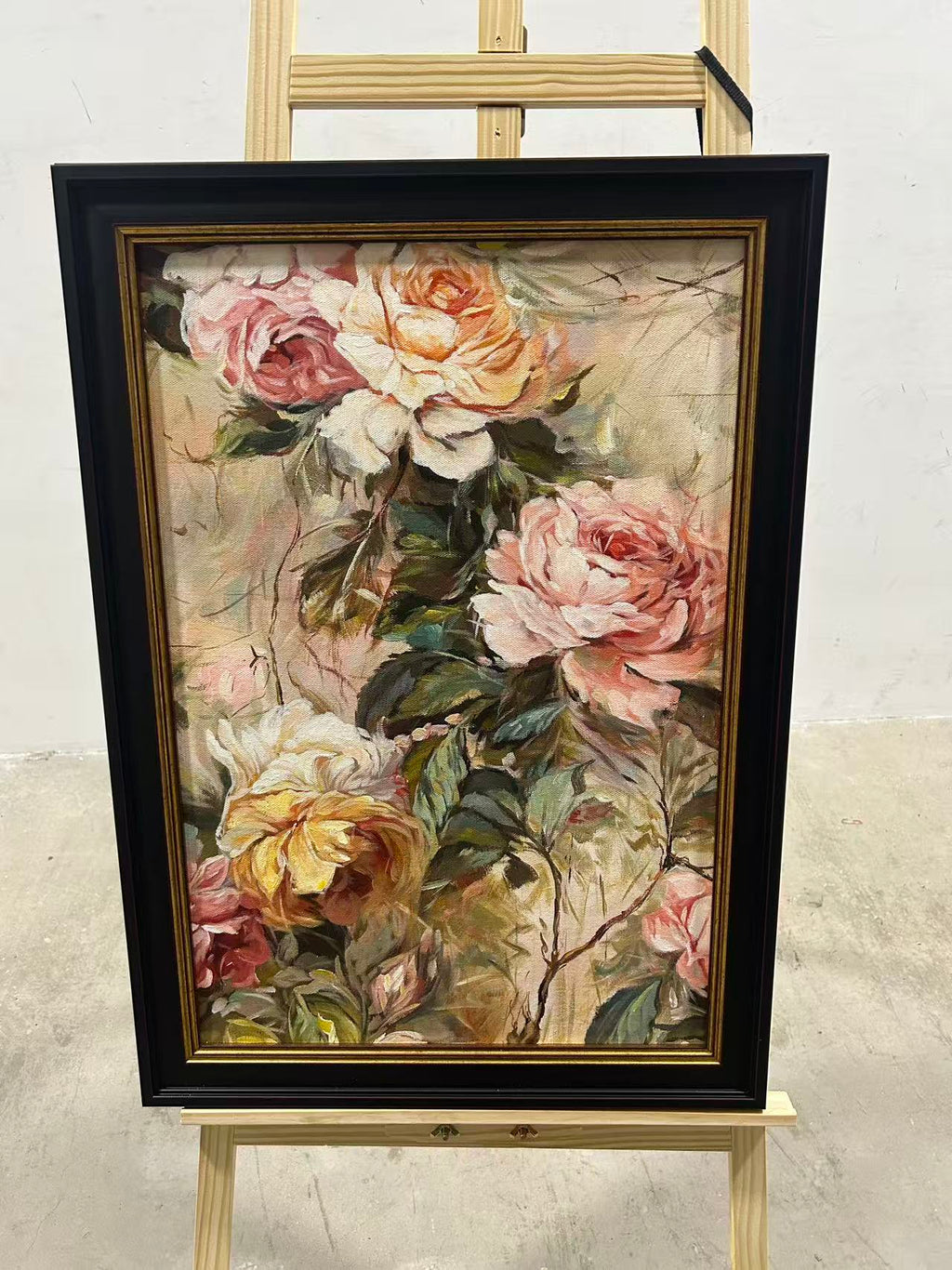 Blush and cream garden roses with lush green leaves in a dark frame.