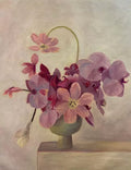 Pink and plum orchids spilling from a small green pot on a pale ledge