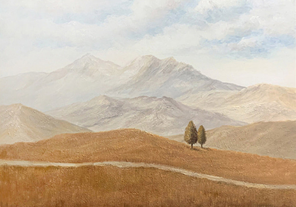Two small cypress trees on golden rolling hills below hazy grey mountains