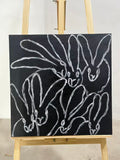 A white one-line drawing of a rabbit and reaching hands on a black ground.