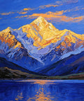 A snow peak lit gold and orange at sunset above deep blue ridges and a glowing lake