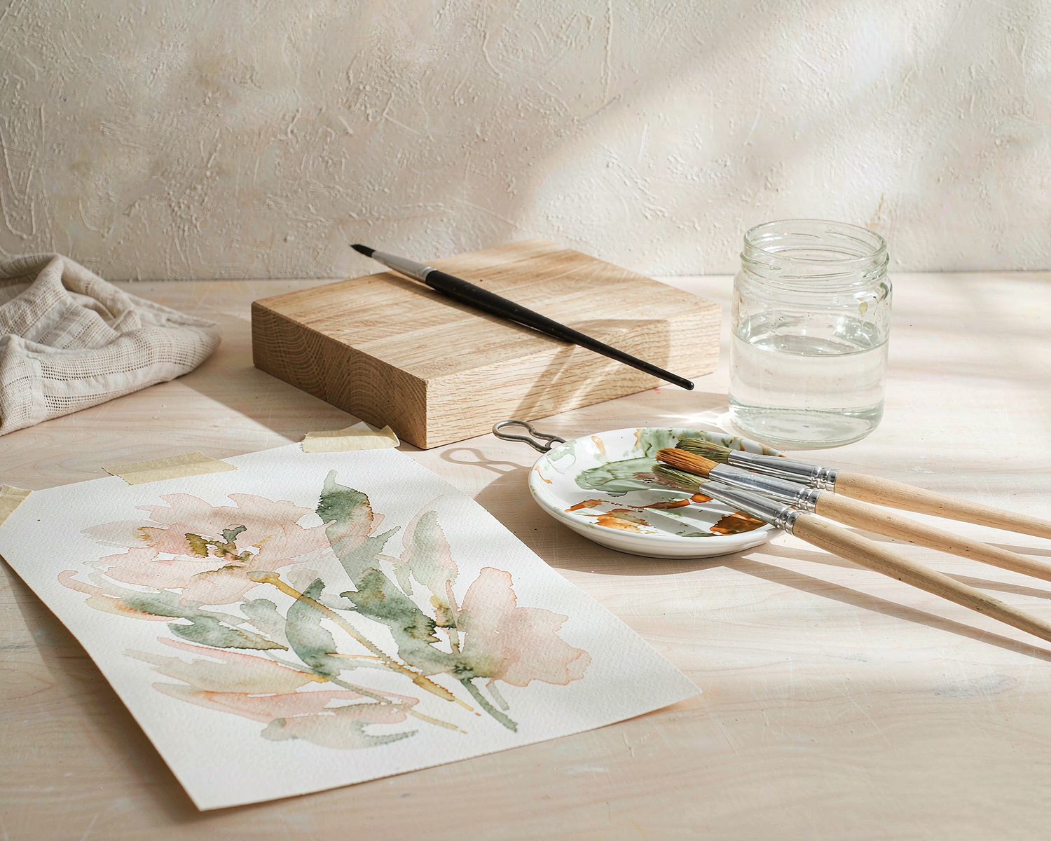 Watercolor paper, brushes and pigments on a bright worktable